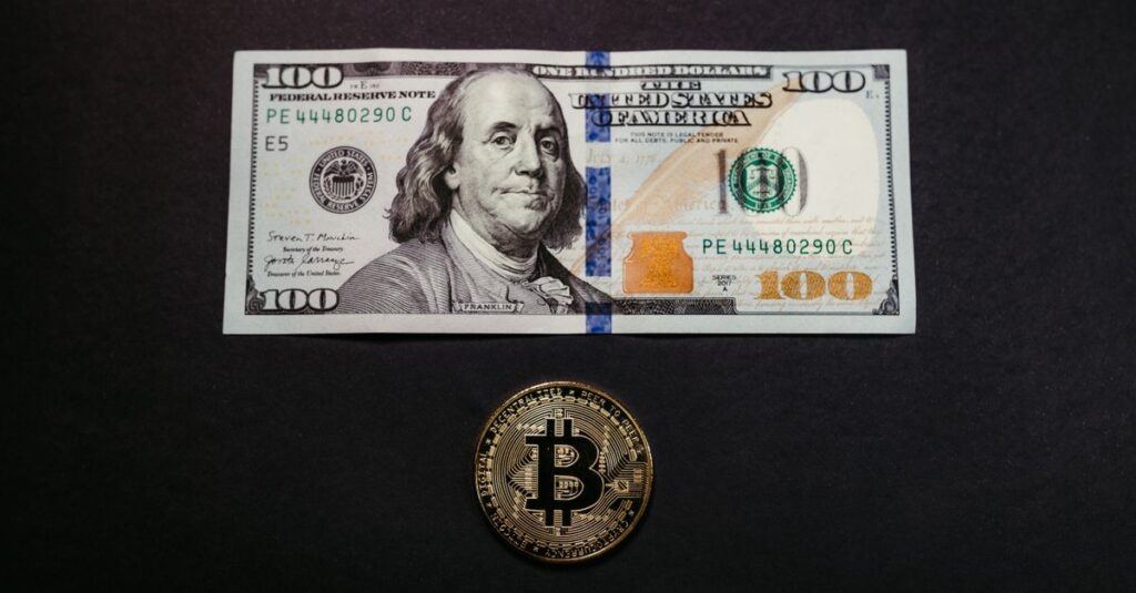 Image of a US 100 dollar bill and a Bitcoin coin on a black background, symbolizing traditional and digital currency.