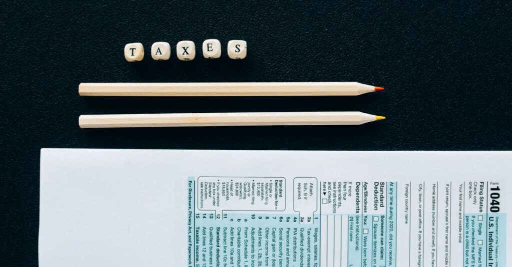 Flat lay of 1040 tax form with pencils and 'TAXES' blocks on black background.