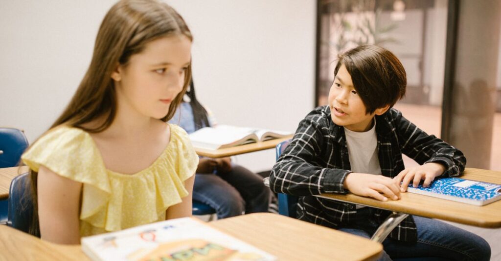 Two students in a classroom interacting with each other during a lesson.